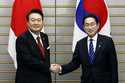 South Korean President Yoon Suk Yeol, left, and Japanese Prime Minister Fumio Kishida shake hands a…