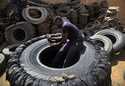 A Sudanese man cuts a heavy duty machine tire into rubber pieces at a shop in a market in Omdurman,…