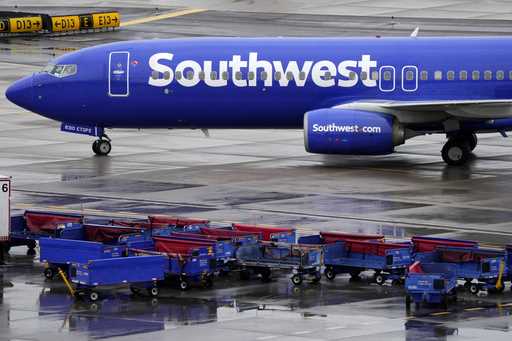 A Southwest Airlines jet passes luggage carts as it arrives, December 28, 2022, at Sky Harbor Inter…