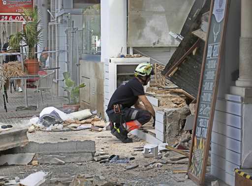 A firefighter looks at part of a collapsed building that killed four people in Palma de Mallorca, S…