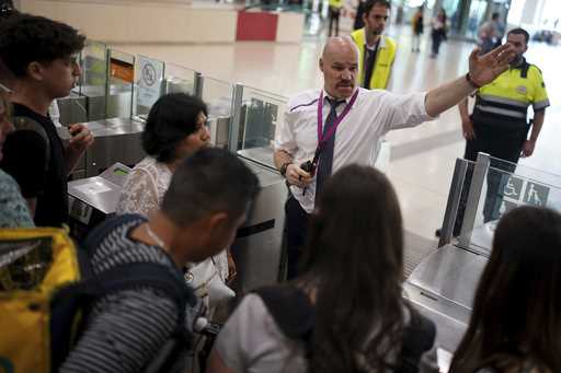 Employees try to give directions to passengers crowded at the entrance to the platforms, at Sants t…