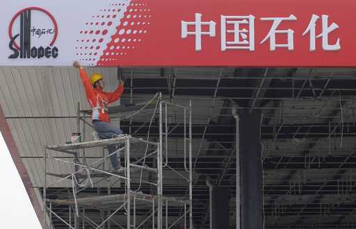 A Chinese worker labors on a Sinopec sign board at a gas station in Huai'an, eastern China's Jiangs…