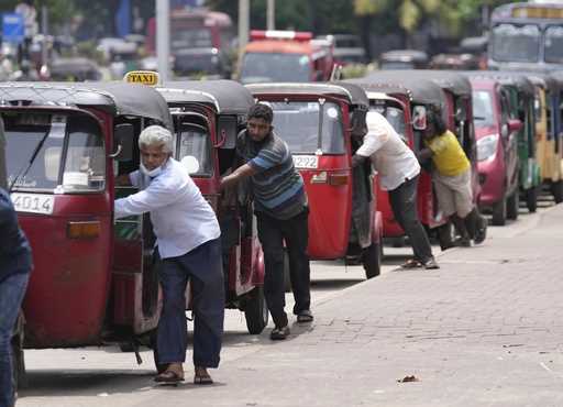 FILE- Sri Lankan auto rickshaw drivers queue up to buy petrol near a fuel station in Colombo, Sri L…