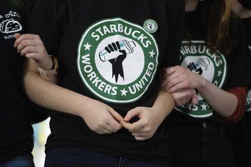 Starbucks employees and supporters link arms during a union election watch party December 9, 2021, …