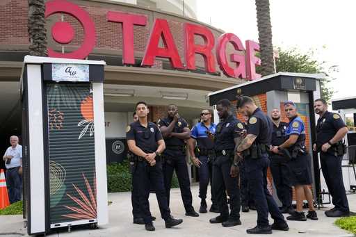 Police officers stand outside of a Target store as a group of people across the street protest agai…