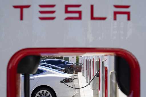 File - Tesla vehicles charge at a station in Emeryville, Calif