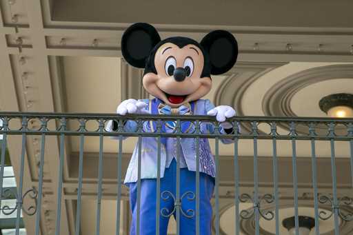 An actor dressed as Mickey Mouse greets visitors at the entrance to Magic Kingdom Park at Walt Disn…
