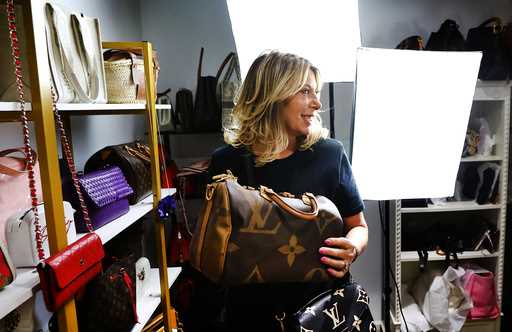 Deborah Mayer holds one of the luxury handbags she sells on TikTok, Wednesday, March 21, 2024, in F…