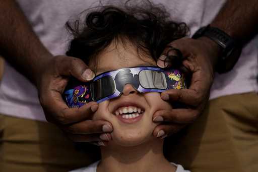 Viewers use special glasses to watch from San Antonio, as the moon moves in front of the sun during…