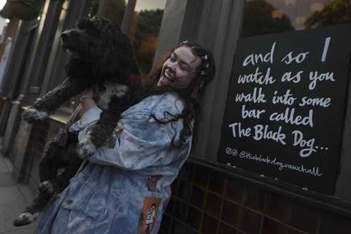Taylor Swift fan Brodie MacArthur from east London poses with a friend's dog next to a sign featuri…