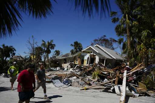 Men walk past destroyed homes and debris as they survey damage to other properties, two days after …