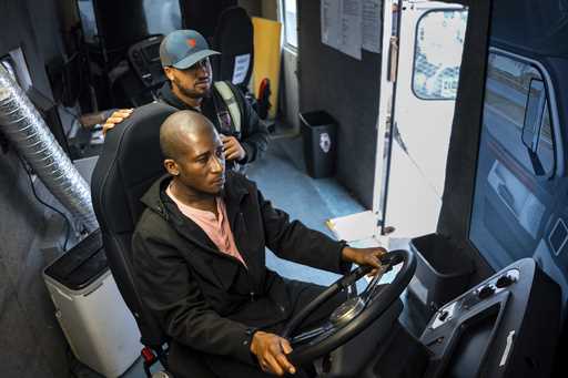 Trucking student Mohammed Kamal, left, overseen by instructor Tom Panton, practices driving a tract…