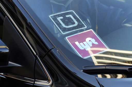 A ride share car displays Lyft and Uber stickers on its front windshield in downtown Los Angeles, J…