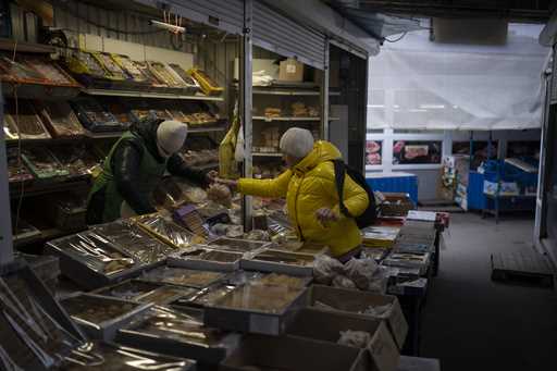 A woman buys from a vendor at a market in Kyiv, Ukraine, Monday, January 30, 2023