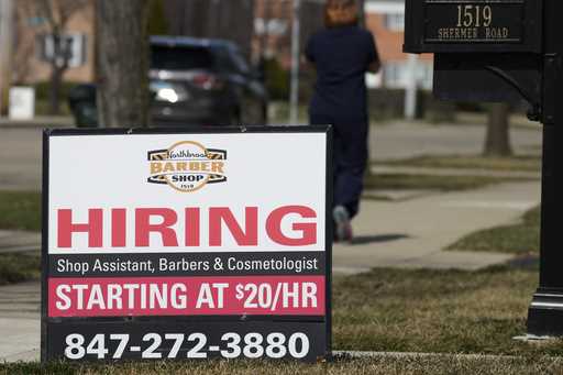 A hiring sign is seen outside of a barber shop in Northbrook, Ill