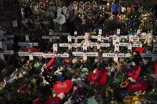 Flowers are piled around crosses with the names of the victims killed in a school shooting as peopl…