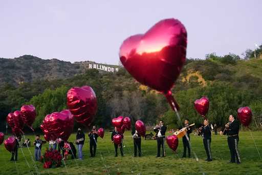 A Mexican Mariachi band surrounded by heart-shaped balloons awaits the arrival of a couple's weddin…