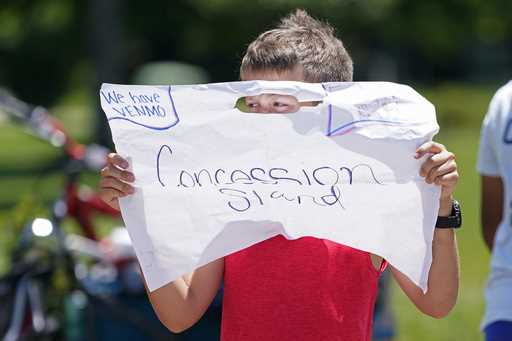 File - Andrew Addison holds up a sign advertising that he takes Venmo for payment at his corner dri…