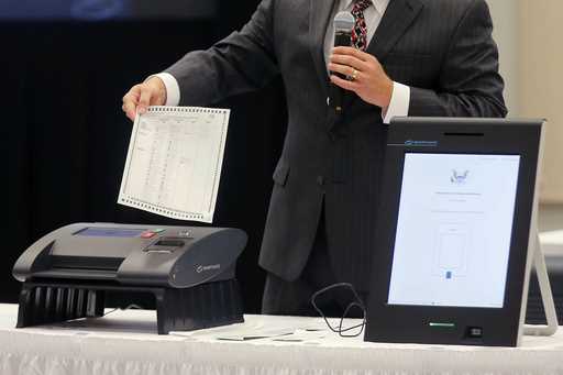 A Smartmatic representative demonstrates his company's system, which has scanners and touch screens…