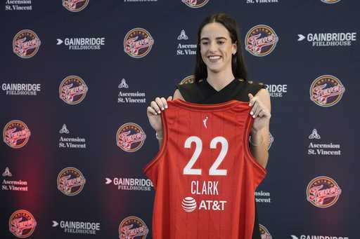 Indiana Fever's Caitlin Clark holds her jersey following a WNBA basketball news conference, Wednesd…