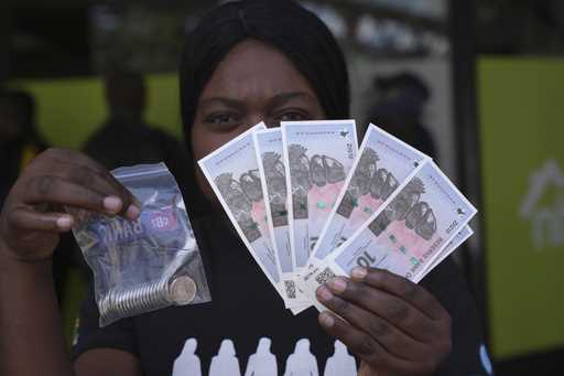 A woman holds the new Zimbabwean banknotes and coins called the ZiG, in the streets of Harare, Zimb…