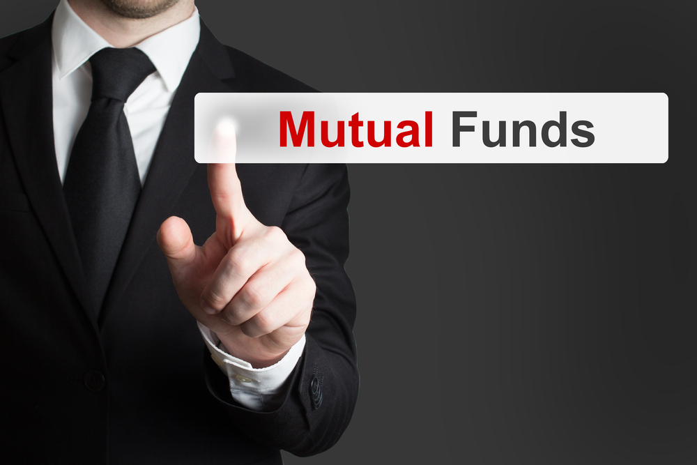businessman in office pushing touchscreen button mutual funds. Learn 
