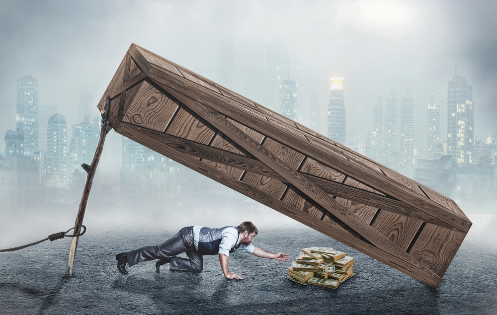 Businessman trying to get money under big wooden box trap. What is a Liquidity Trap?