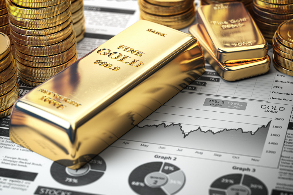 Photo of a gold bar, gold ingots, and gold coins on a financial report. How to invest in gold.