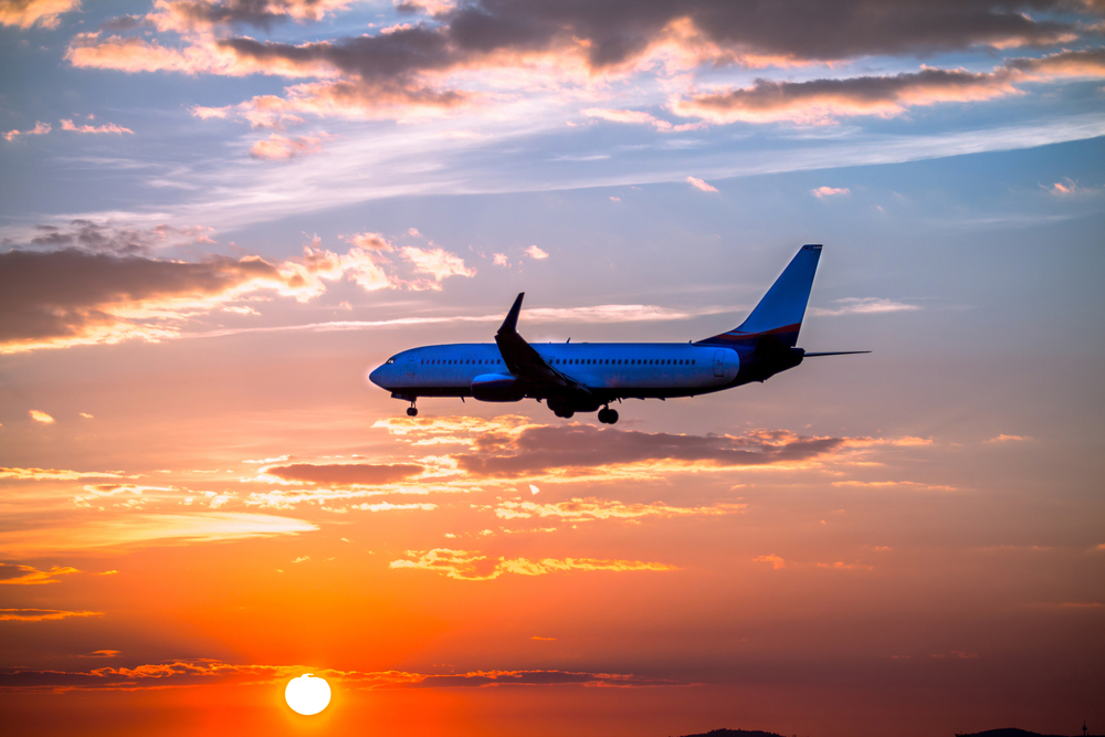 Airplane landing with clouds in the sky at sunset