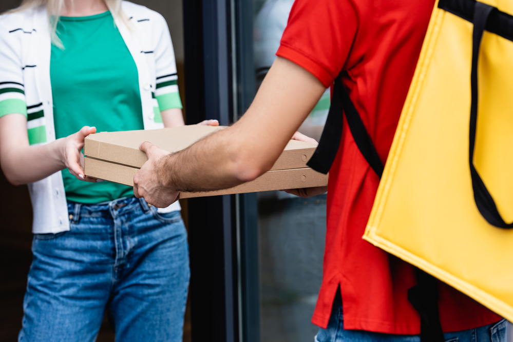 Delivery person handing pizza boxes to customer