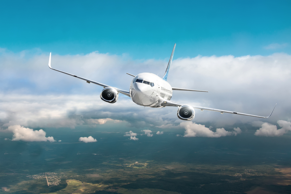 Passenger airplane fly in overcast clouds and blue sky