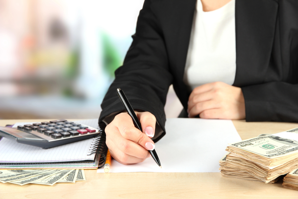 person accounting with paper and dollar bills