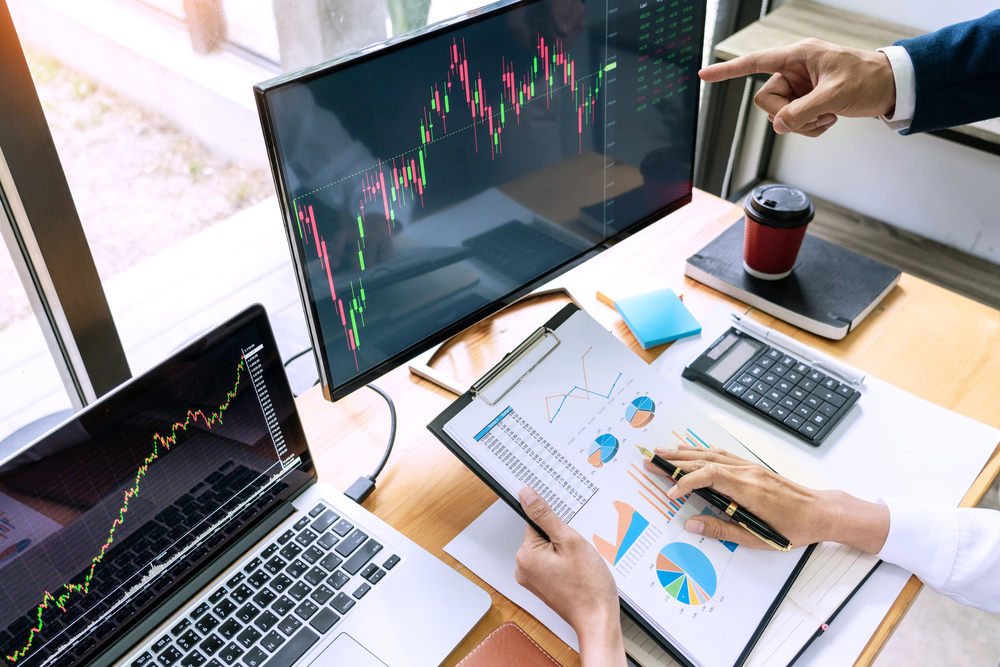 Team of stockbrokers Discussing with display screens Analyzing data, graphs and reports of stock market trading for investment