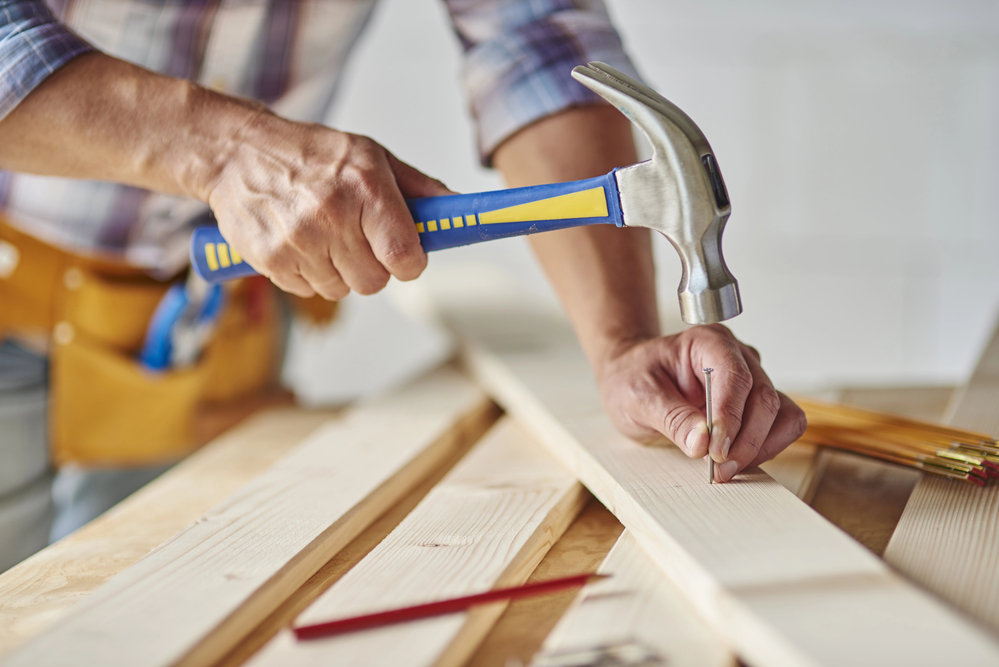 Carpenter with hammer doing woodwork
