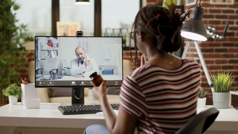 African american woman meeting with medic on videocall, attending telemedicine videoconference with webcam to discuss about healthcare and treatment. Online telehealth conference.