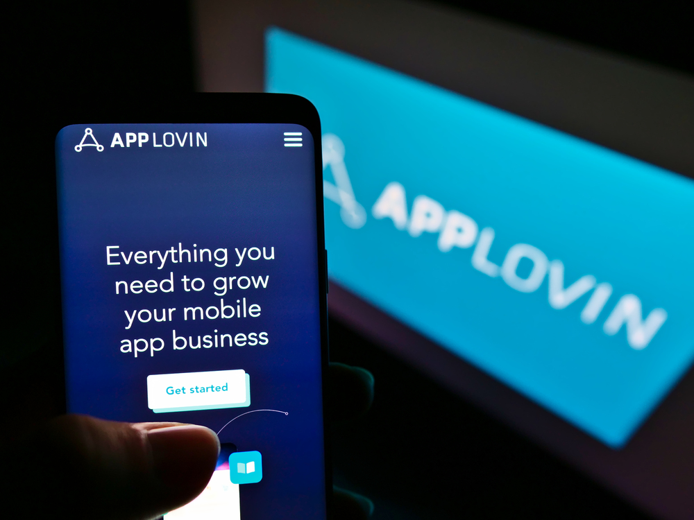 Person holding mobile phone with website of technology company AppLovin Corp. on screen with logo