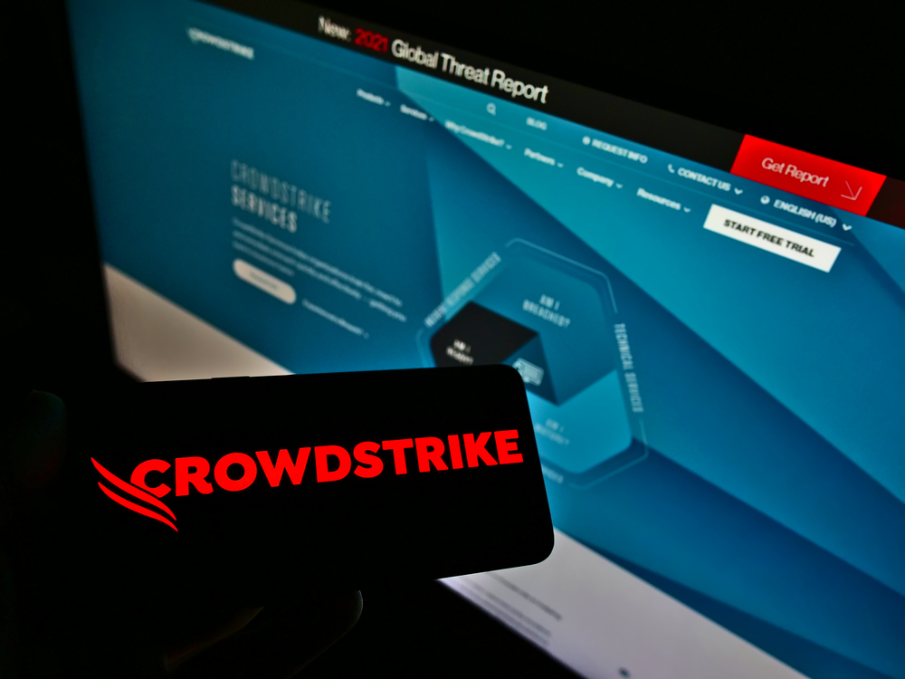 Person holding smartphone with logo of US software company CrowdStrike Holdings Inc. on screen in front of website