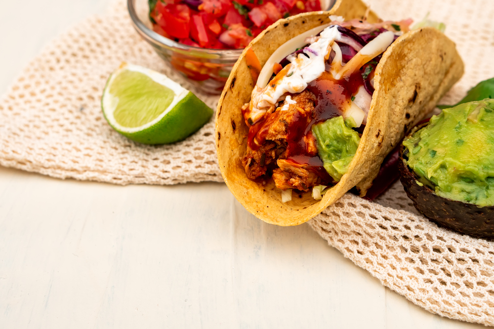Mexican traditional authentic homemade tacos with pulled pork beef chili con carne serve with tomato salad and avocado guacamole and dip sauce