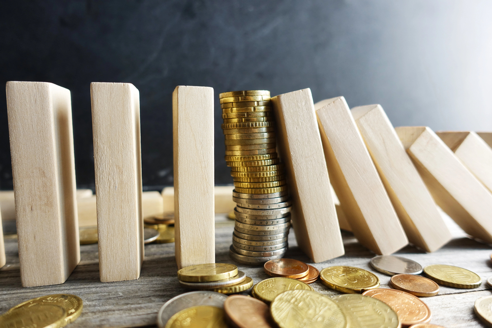 Financial stability concept with pile of money between wooden pieces with domino effect — Photo