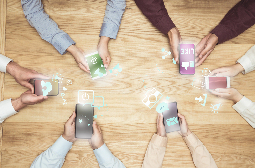 Photo of people holding smartphones with social media apps on them.