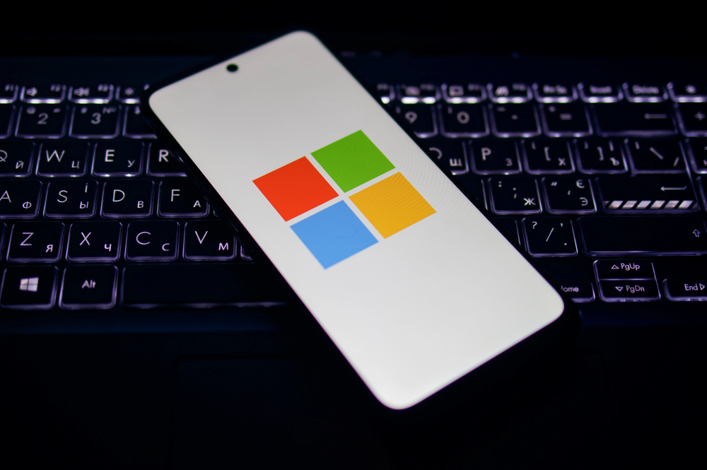 Kherson reg, Ukraine on September 19, 2024 Illustration photo of close-up Microsoft logo icon displayed on a screen of smartphone laying on the illuminated laptop keyboard - Stock Editorial Photography