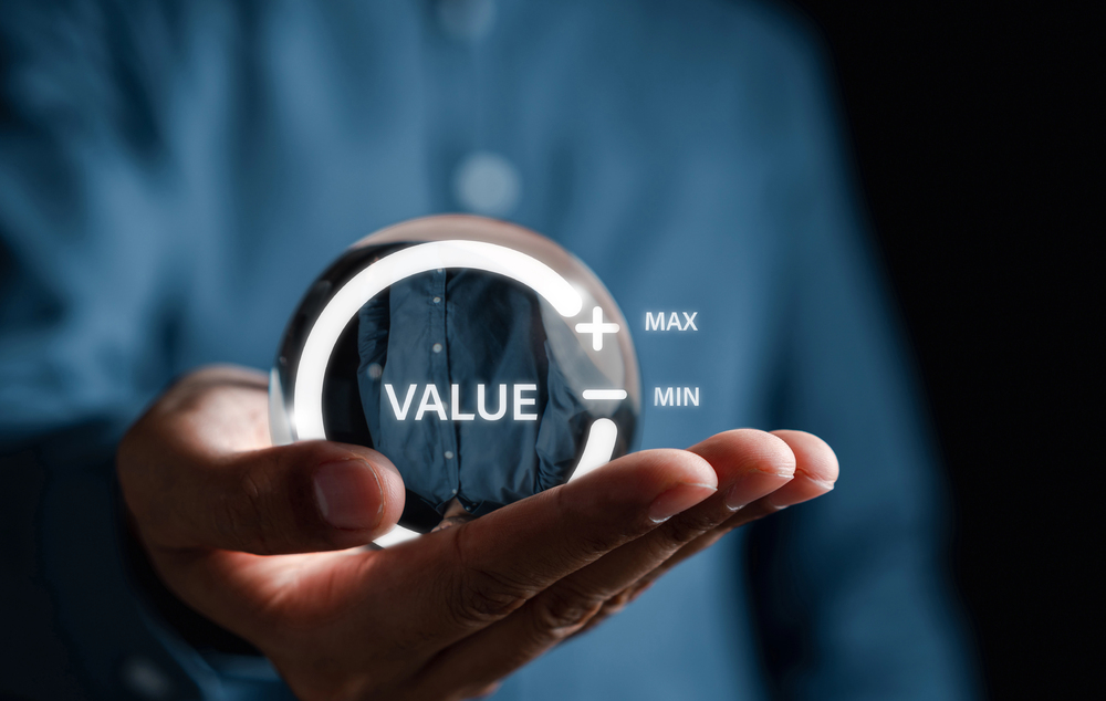 Photo of someone holding a hologram of the world "value" enclosed in a circle with plus and minus signs