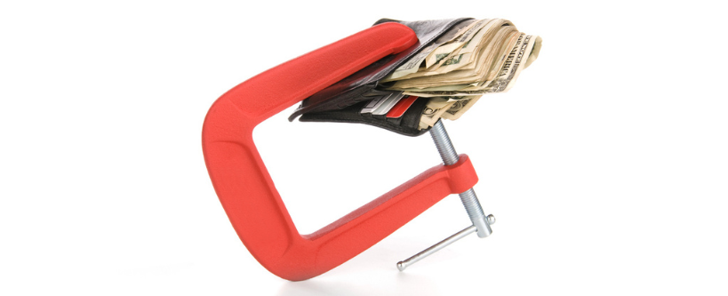 Photo of a clamp around a wallet filled of money.