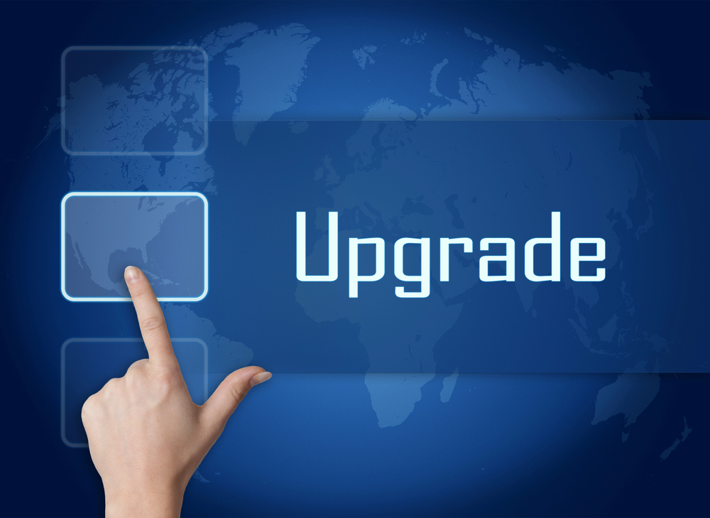 Photo of the word Upgrade on a blue background, a finger pressing a button next to it