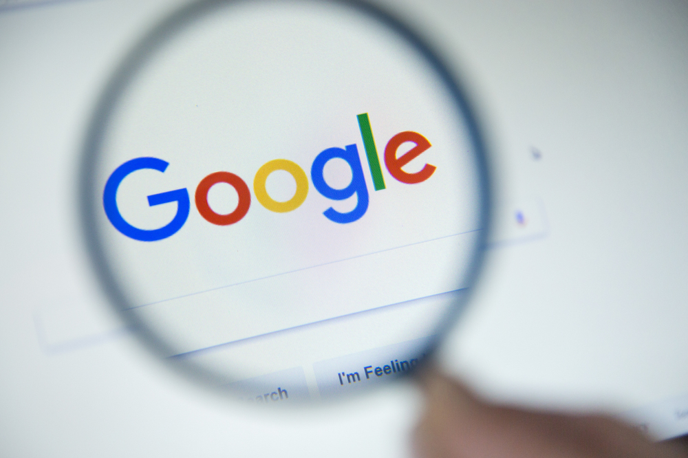 Google.fr homepage on the screen under a magnifying glass. Google is world's most popular search engine