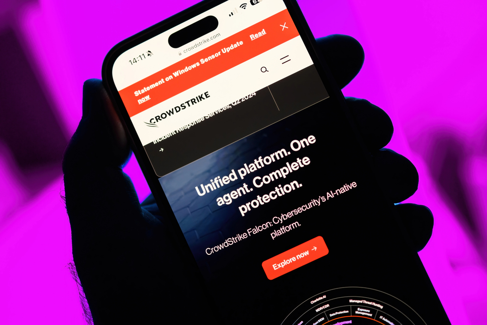 Paris, France - Jul 20, 2024: From a point-of-view perspective, a male hand holds an iPhone showing a CrowdStrike webpage about their role in addressing a major global IT outage, against a magenta — Stock Editorial Photography