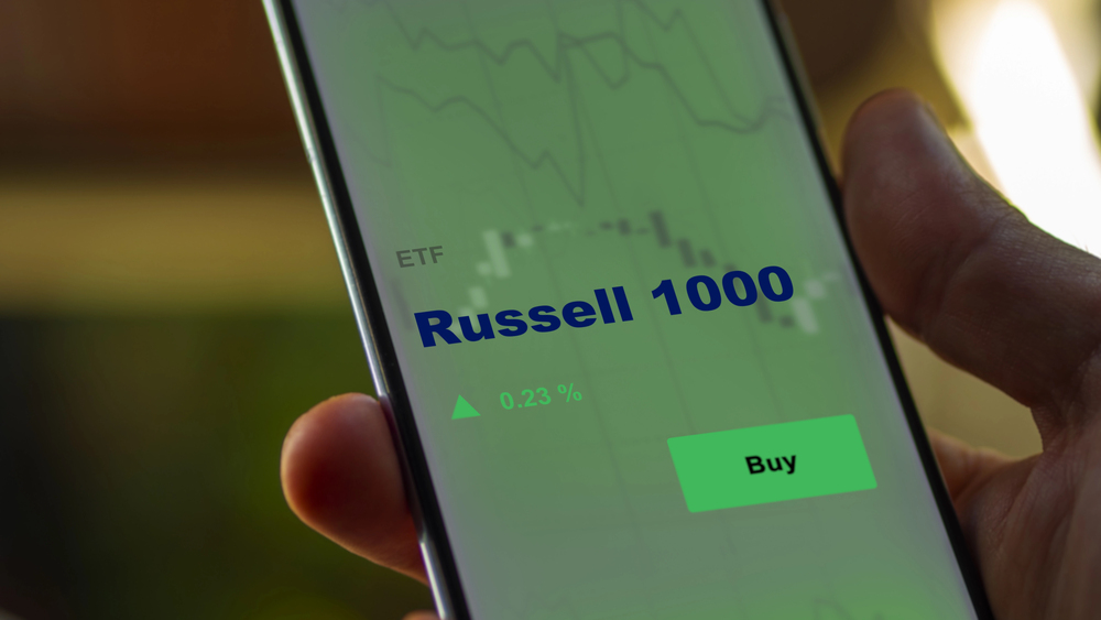 An investor analyzing the russell 1000 etf fund on a screen. A phone shows the prices of Russell 1000 — Stock Editorial Photography
