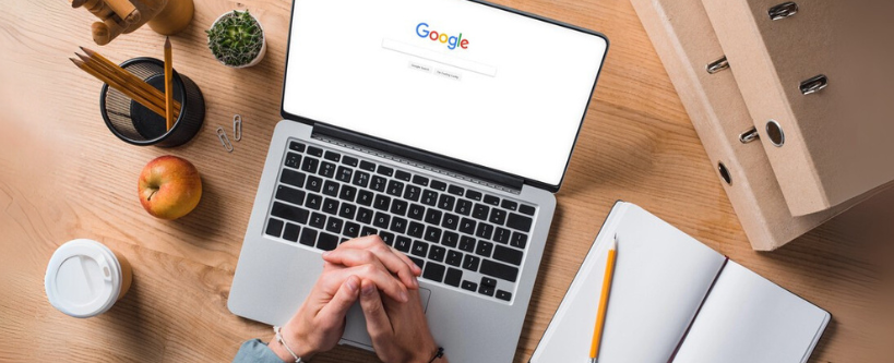 Cropped shot of businessman sitting at workplace with laptop, google website on screen