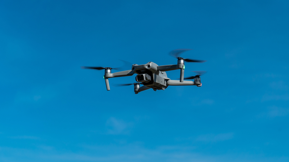A modern drone flying in the cloudy blue sky — Photo