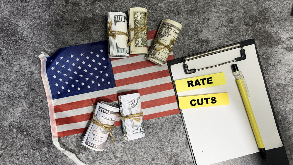 Concept of Rate Cuts write on sticky notes and Flag of the United States isolated on Wooden Table.